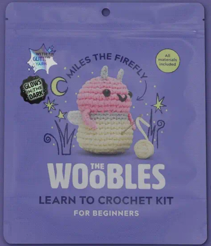 Purple crochet kit packaging featuring a cute pink and cream firefly plush that glows in the dark