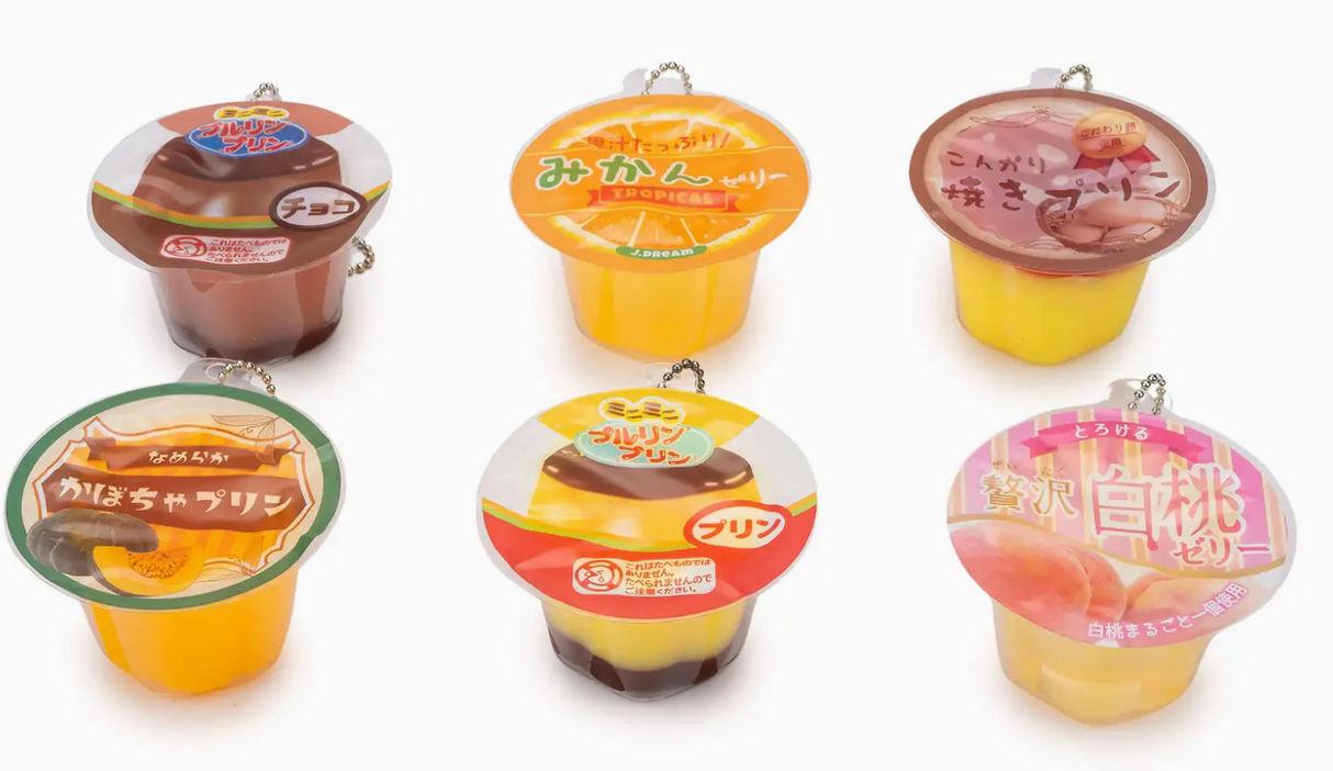 Six colorful squishy pudding jelly cup capsules with keychains in various fruit and dessert designs