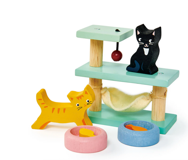Two wooden toy cats with pastel play table, hanging ball, and pink and blue bowls with fish food pieces