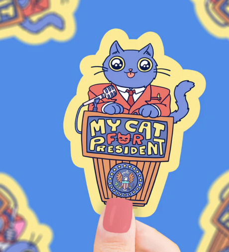 Sticker of a cartoon cat in a suit standing behind a podium that says My Cat for President with a microphone