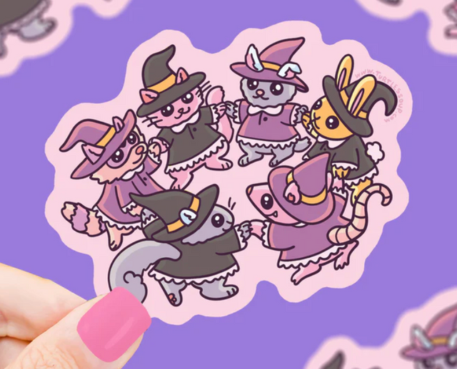 Cute woodland animals dressed as witches holding hands in a circle on a small decorative sticker