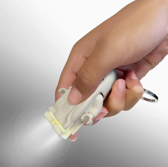 Hand holding a posable ghost LEGO keychain with LED lights shining from its feet and attached metal ring