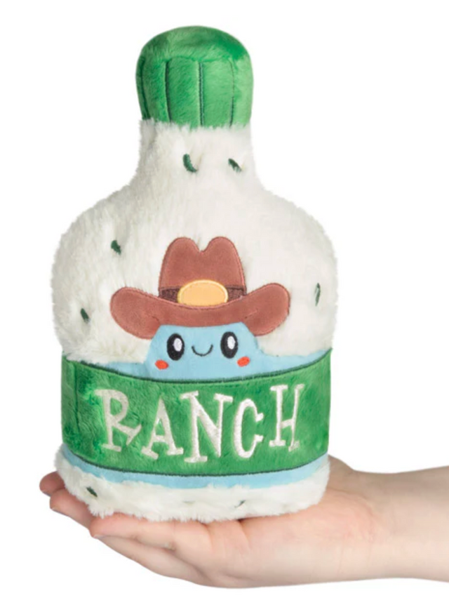 Hand holding a cute plush bottle of ranch dressing with a cowboy hat and green label reading ranch