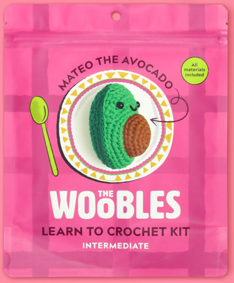 Pink packaging of The Woobles Mateo the Avocado crochet kit with an image of the crocheted avocado on a decorative plate