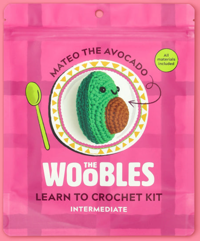 Pink packaging of The Woobles Mateo the Avocado crochet kit with an image of the crocheted avocado on a decorative plate