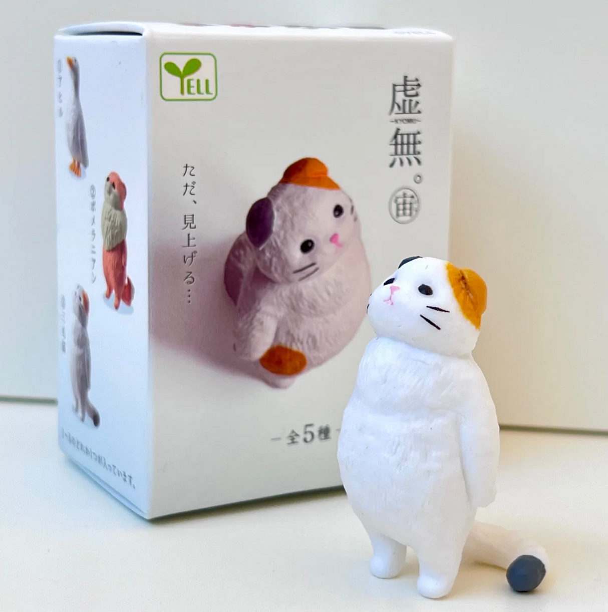 Small white cat figurine standing on hind legs next to Sky Void Animal Blind Box by Yell Japan