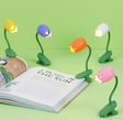 Assorted colorful tulip-shaped book lights with flexible arms clipped to a book, illuminating its pages gently