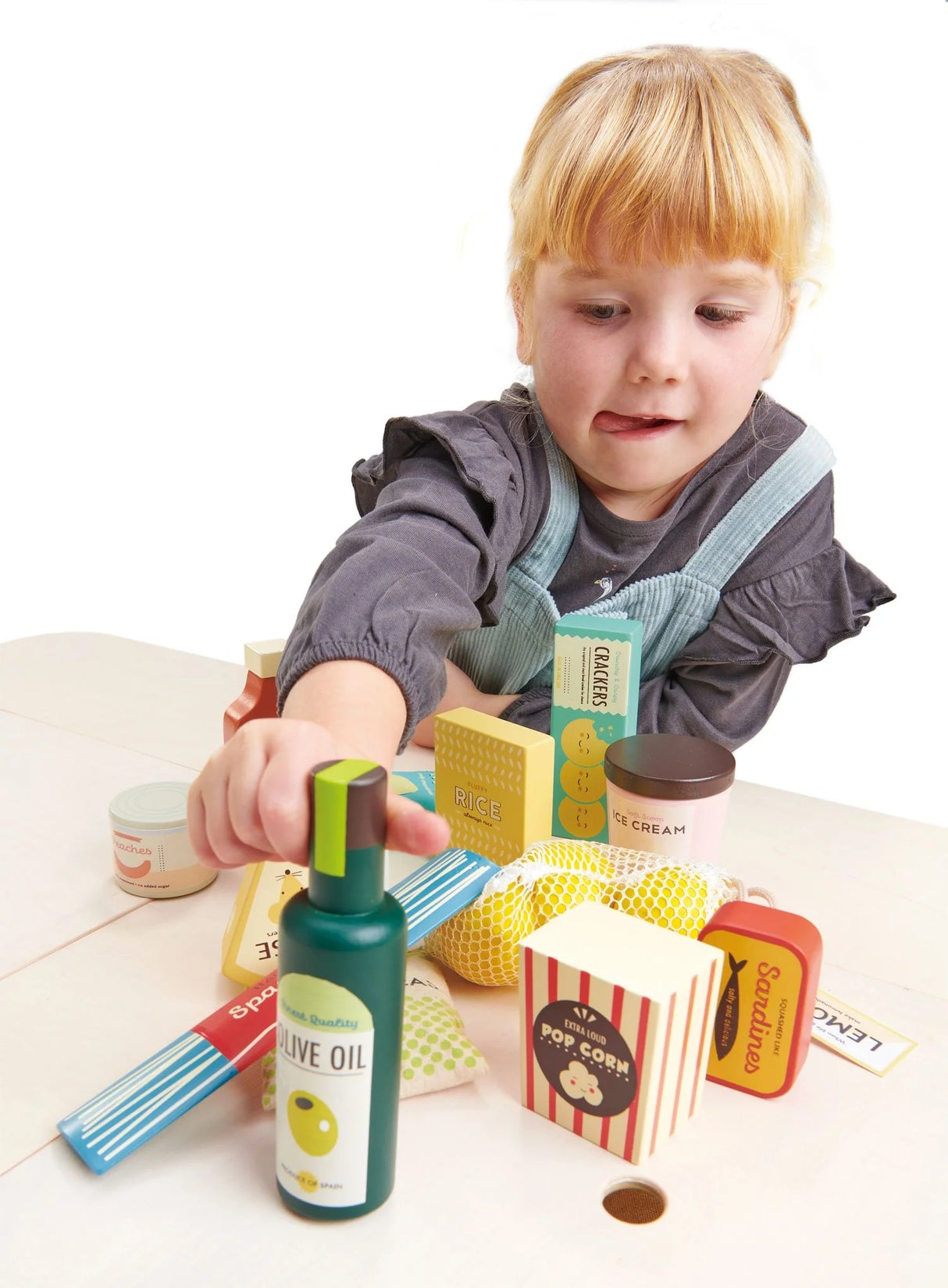 Child playing with a Tender Leaf Supermarket Grocery Set featuring illustrated food items like olive oil and popcorn.