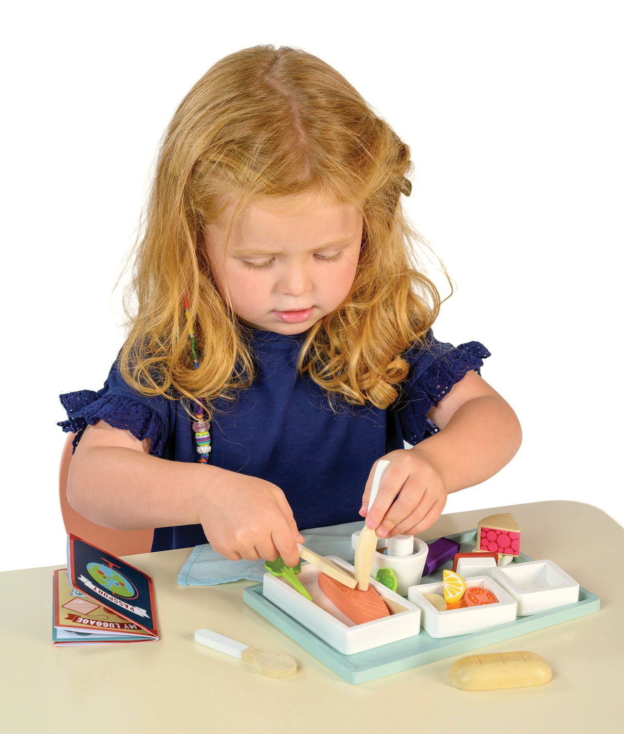 Young child playing with the Airline Meal Tray featuring a three-course meal and cutlery on a tray.