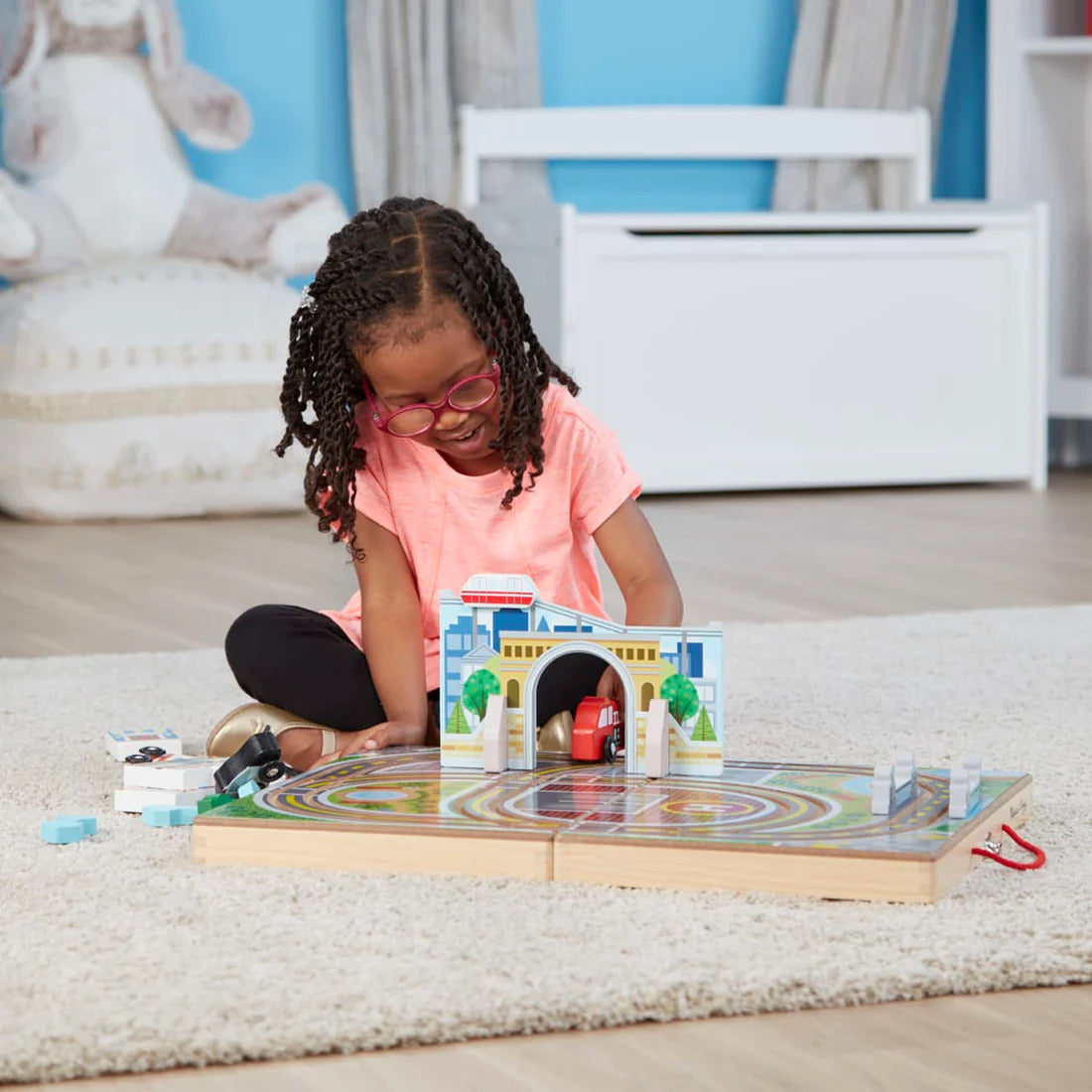 Child playing with wooden vehicles and road tracks on a foldable board in the Take Along Town playset.