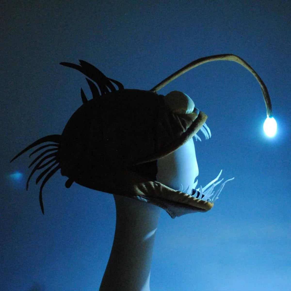 Light-Up Angler Fish Jawesome Hat glowing in dark, soft material with adjustable fit and illuminated lure detail.