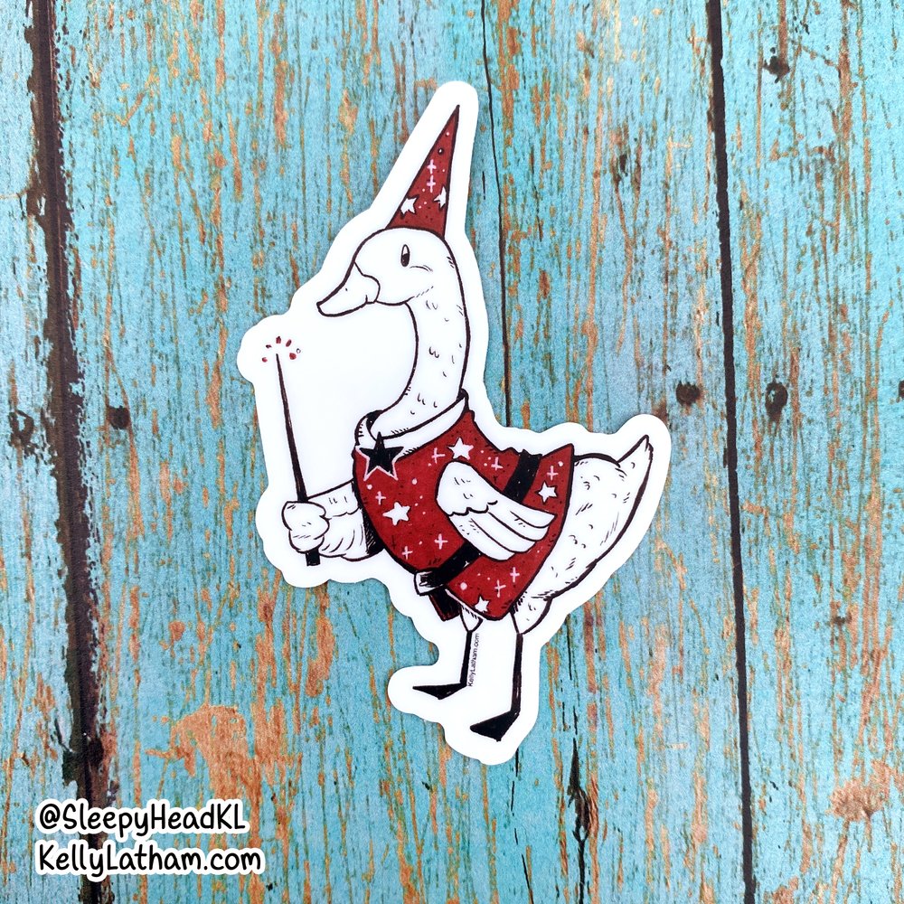 Wizard Duck Sticker featuring a white duck in a red wizard hat and robe holding a magic wand on wood background.