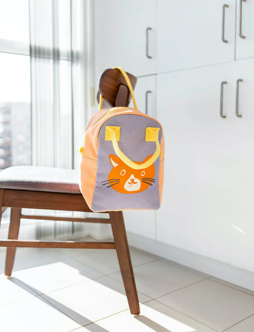 Zipper Lunch Bag | Cat with orange cat design hanging on a wooden chair in a bright kitchen setting
