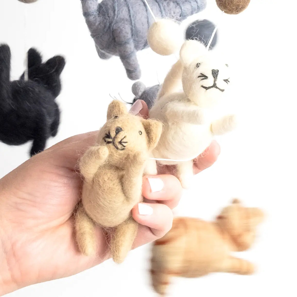 Hand holding felt cat figures from the Felt Mobile | Cats & Mouse nursery decor, natural wool mobile hanging.