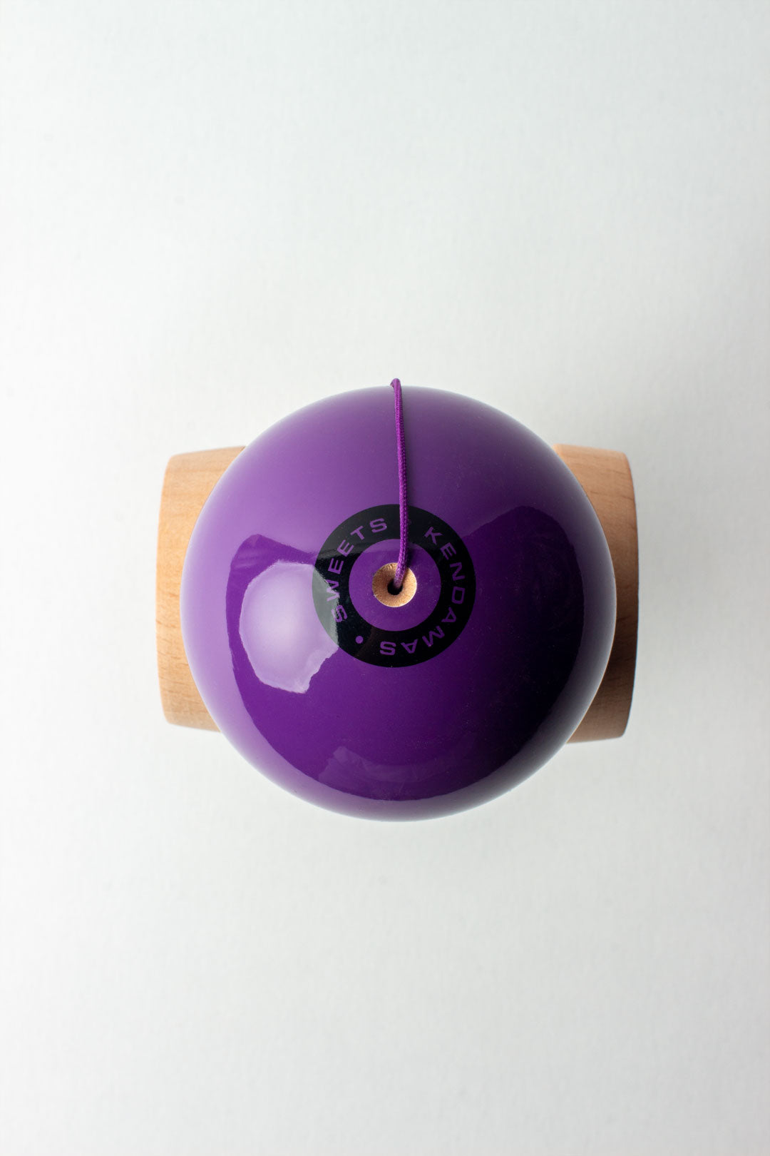 Kendama Starter Purple with glossy purple tama and natural wood ken shown from top view with string attached.