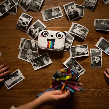 Print & Digital Camera Model P | Koko the Panda surrounded by black-and-white instant printed photos on a wooden surface.