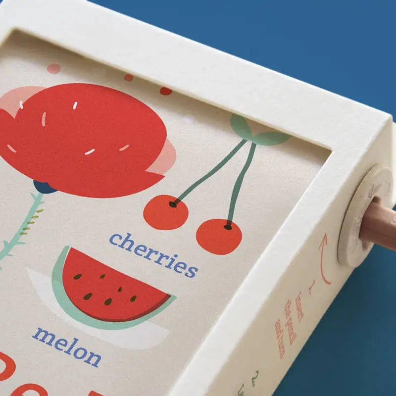 Scrollino Colors Learning Book showing colorful fruit illustrations including cherries and melon on eco-friendly scroll.