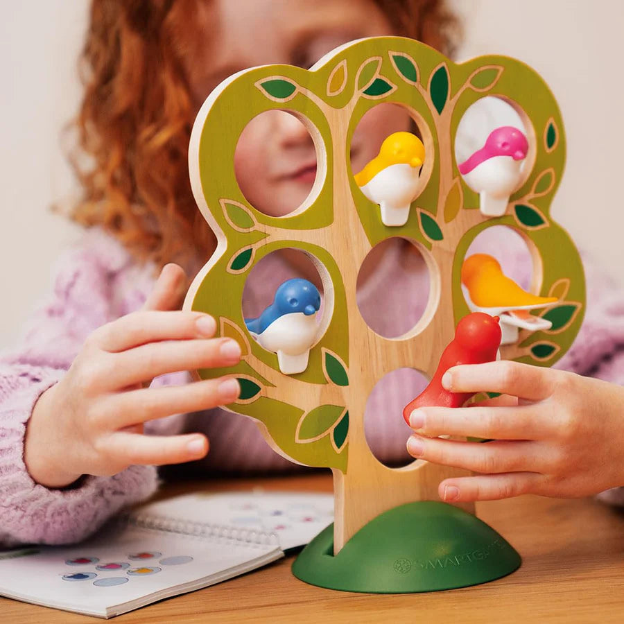Child playing with colorful bird pieces on wooden tree puzzle game 5 Little Birds improving logic skills