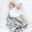 Organic Muslin Swaddle | Forest with black and white animal print wrapped around a smiling baby lying on a white blanket