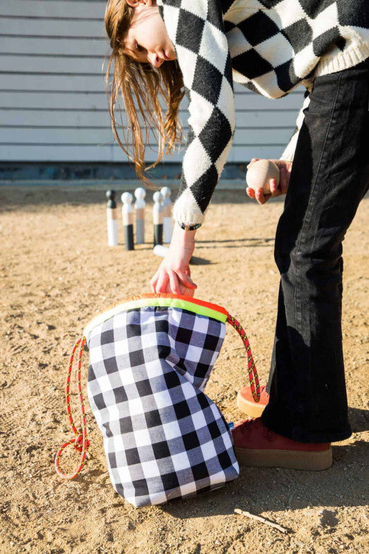 Bowling set featuring wooden pins and balls with a checkered storage bag for classic outdoor fun.