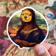 Mona Otter Sticker featuring an otter in Mona Lisa style artwork by Ryan McCulloch, durable and waterproof design.