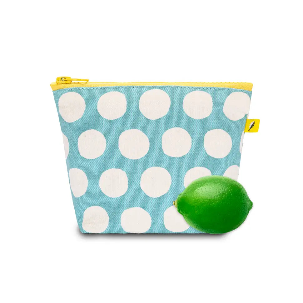 Small blue pouch with white dots and yellow zipper, shown next to a lime for size comparison