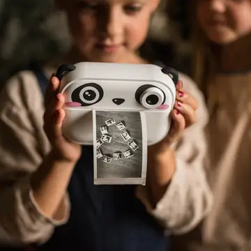 Child holding the Print & Digital Camera Model P | Koko the Panda printing a black-and-white photo instantly.