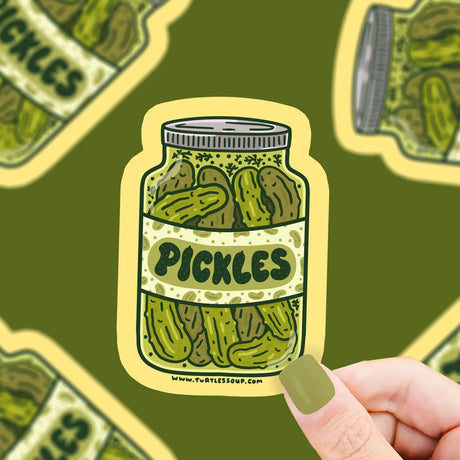 Hand holding a Pickle Jar Sticker showing a vintage-style pickle jar with green pickles on durable vinyl material.