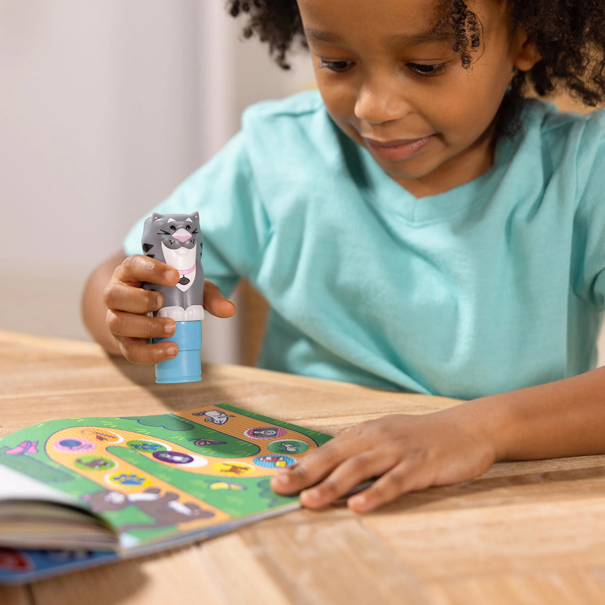 Child playing with a Sticker WOW! Cat stamper on a pets-themed activity book page, focusing on fun learning.