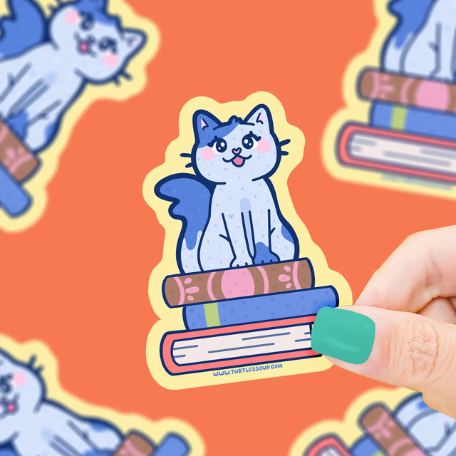 Cat on Stacked Books Sticker showing a cute blue cat sitting on colorful books, printed on durable vinyl for lasting use.
