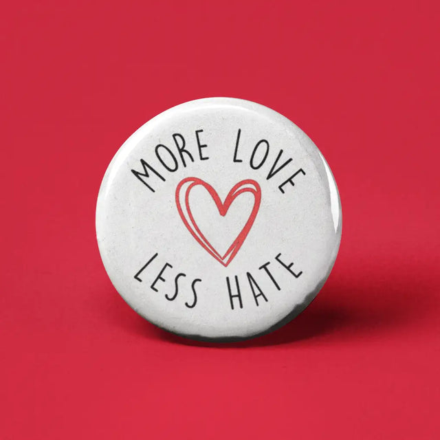 Button | More Love Less Hate white button with red heart and black text on red background, 1.25 inches expressing positivity and kindness.
