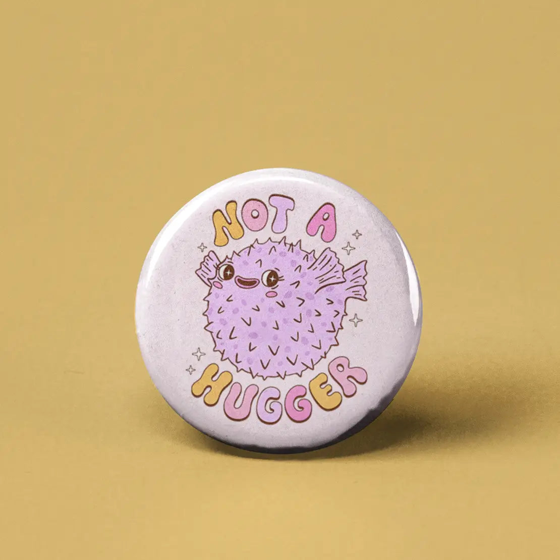 Button | Not a Hugger Pufferfish featuring a cute, spiky pufferfish with "Not a Hugger" text on a round 1.25-inch pin.