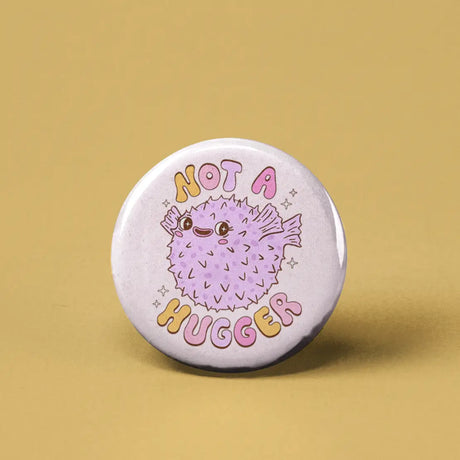 Button | Not a Hugger Pufferfish featuring a cute, spiky pufferfish with "Not a Hugger" text on a round 1.25-inch pin.