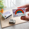Hand holding Somewhere Over the Rainbow Musicbox Matchbook with rainbow and Follow Your Dreams message visible.