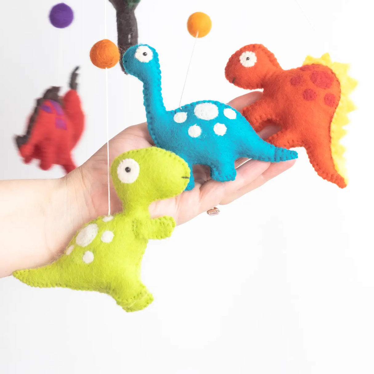 Felt Mobile | Dinosaur showing colorful handmade wool dinosaur figures hanging from strings in a friendly design.