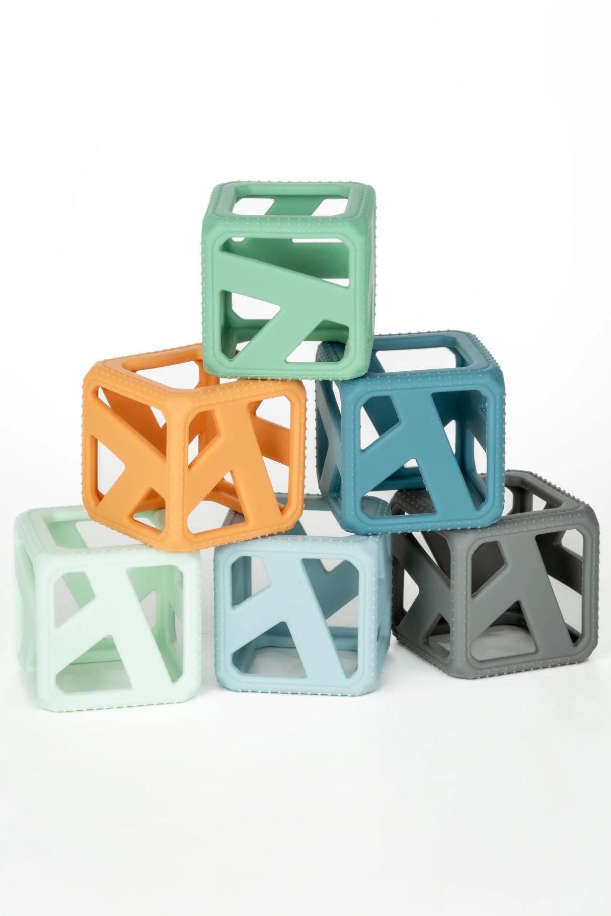 Stack & Chew Earthy Cubes in various colors stacked for teething and developmental play, BPA-free silicone baby toy.