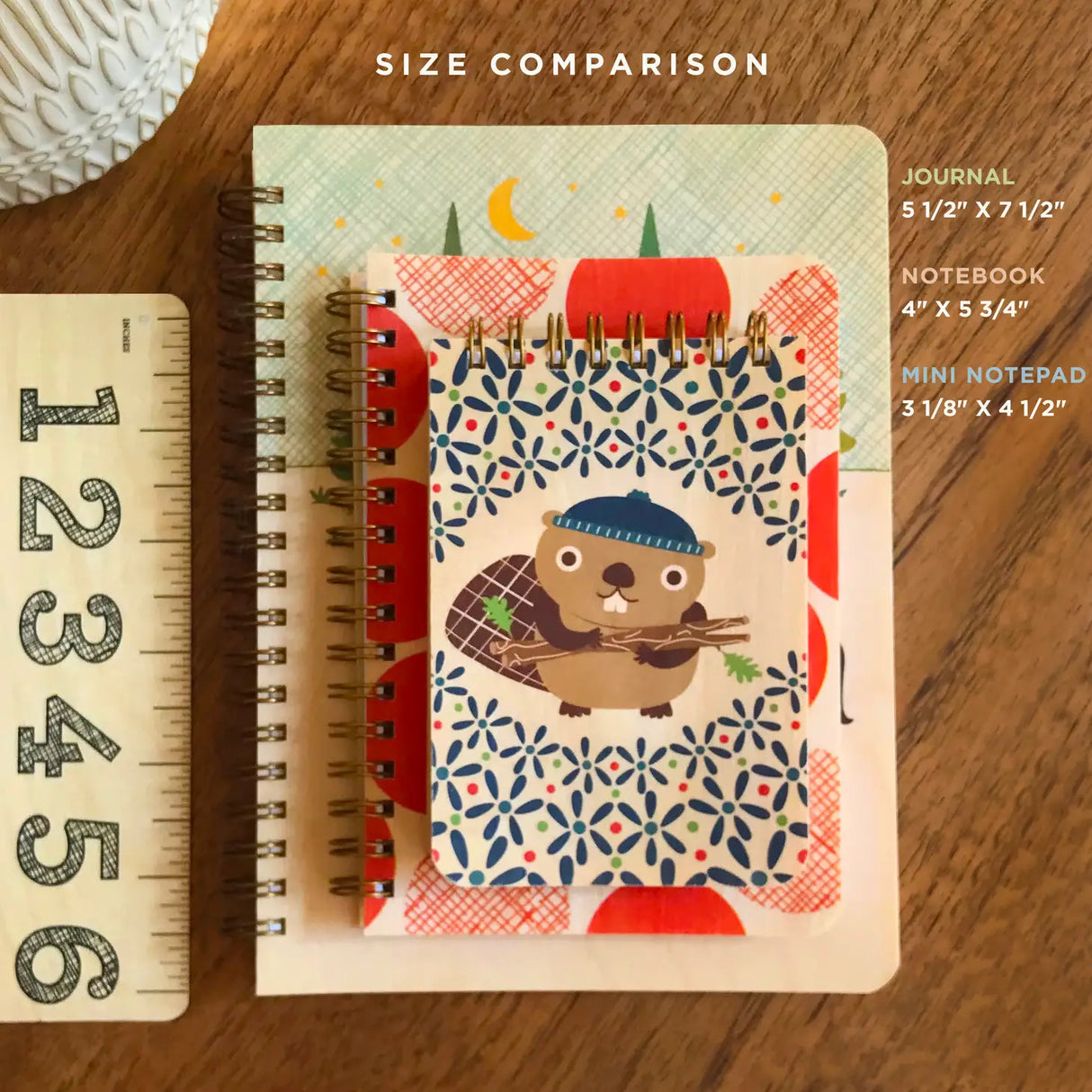 Mini Wood Notebook | Otters with spiral binding and otter design, measuring 3-1/8 by 4-1/2 inches, next to larger journals.