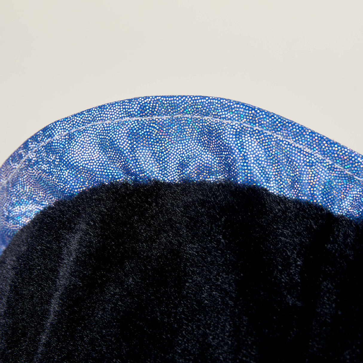 Close-up of soft black plush fabric with shiny blue trim on a Warmies Black Axolotl toy