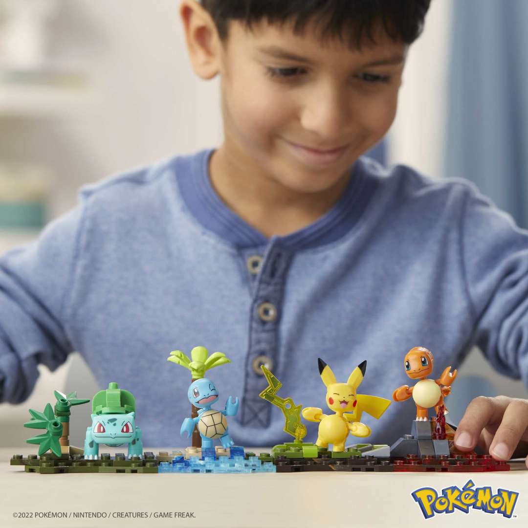 Child playing with Mega Construx Pokemon Kanto Region Team featuring buildable Pikachu, Squirtle, Charmander, and Bulbasaur.
