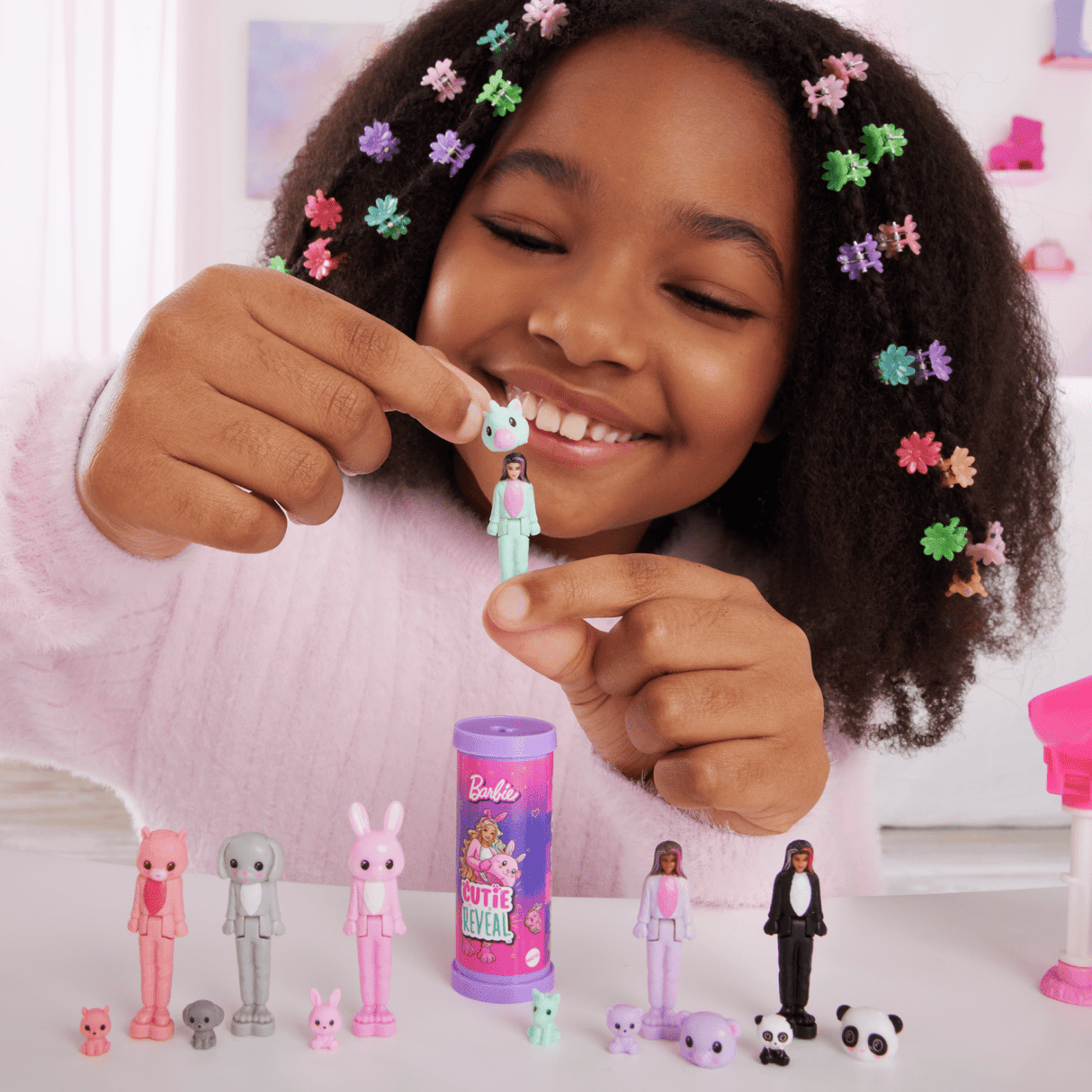 Girl playing with Mini BarbieLand Cutie Reveal doll and animal accessories in a colorful room setting.