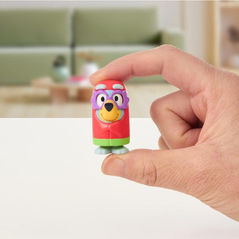 Hand holding a colorful mini figure from the Bluey Mini Figure Mystery Pack in a bright indoor setting.
