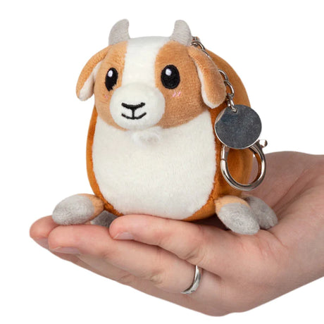 Hand holding the Baby Goat Micro plush keychain with brown and white fur and cute embroidered face.