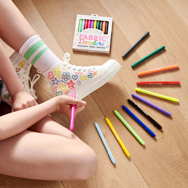 Fabric Doodlers Permanent Fabric Markers shown with colorful doodles on white canvas shoes and open marker set.