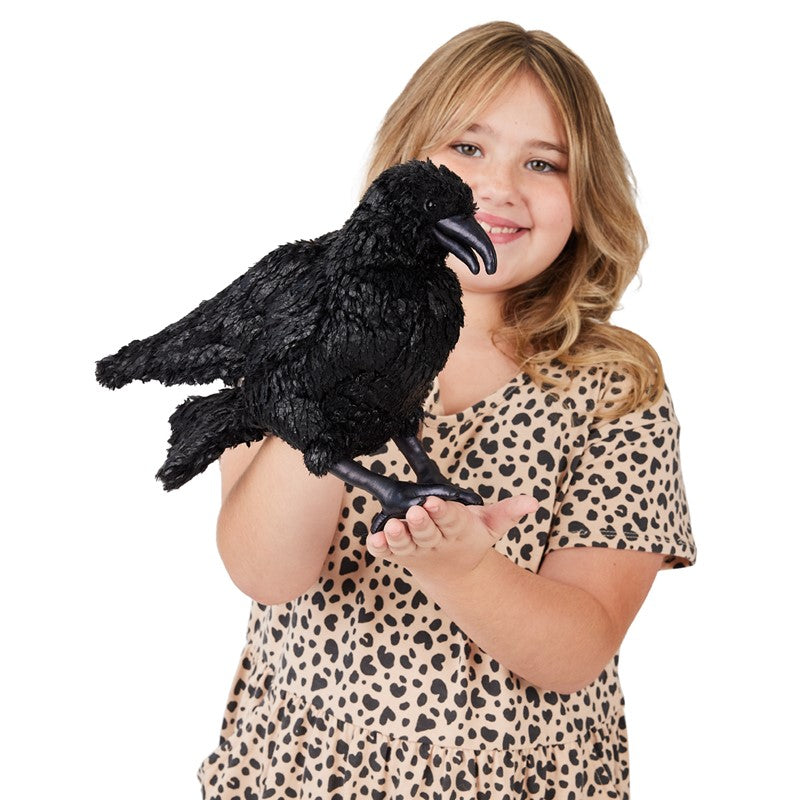 Girl holding a black Crow Puppet with movable beak and shiny legs, resembling a real crow, 11 inches long.