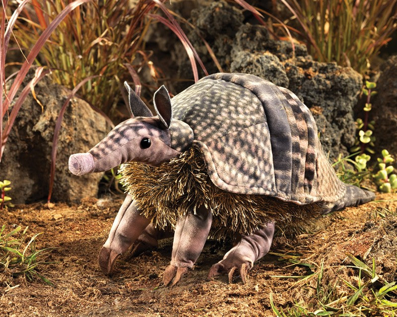 Armadillo Puppet on natural ground with detailed soft fabric showing patterns and a pine-needle textured belly.