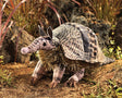 Armadillo Puppet on natural ground with detailed soft fabric showing patterns and a pine-needle textured belly.