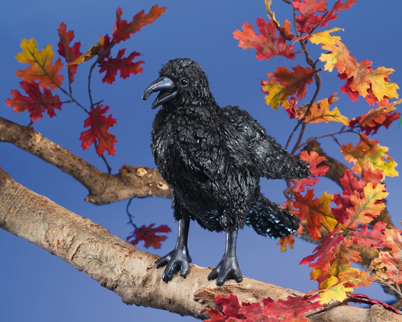 Crow Puppet perched on a branch with detailed black feathers and movable beak against a bright blue sky background.