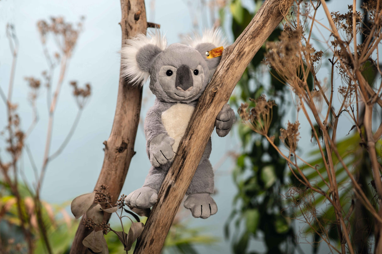 Koala Nils plush toy clinging to a branch, handmade soft grey and white marsupial with fuzzy ears and stitched claws.