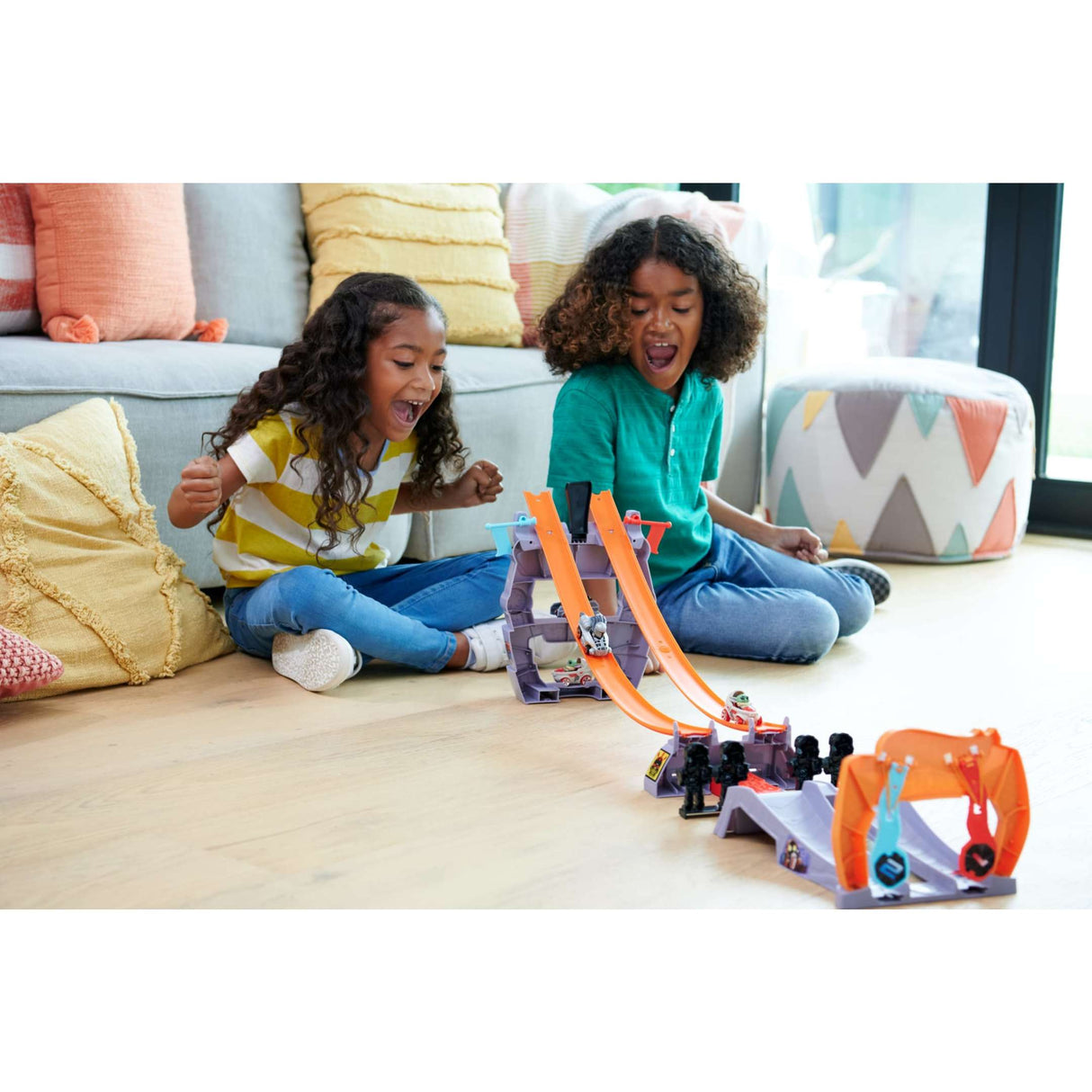 Two kids excitedly play with the Hot Wheels RacerVerse Star Wars Grogu's Great Race track set on the floor.