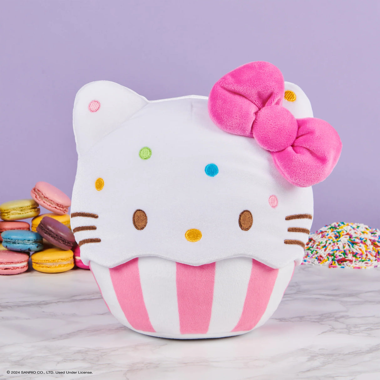Hello Kitty Cupcake plush with a pink bow, rainbow sprinkles, soft texture, and pink-and-white striped baking cup.